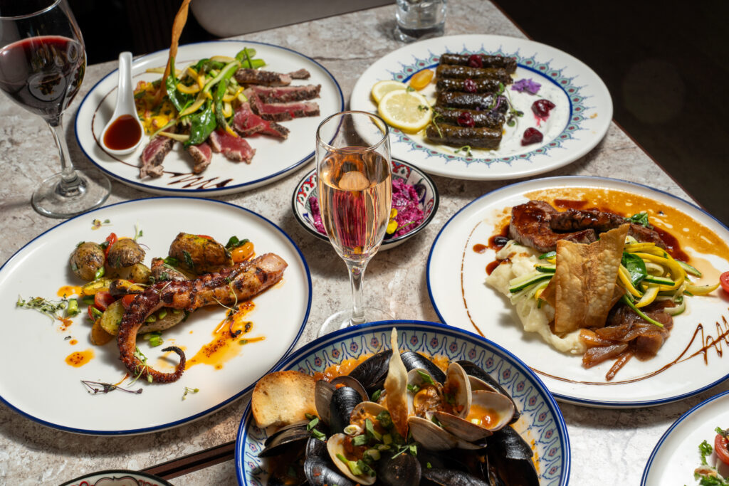 Table set with grape leaves, grilled octopus, mussels and rosé at Olivea Restaurant
