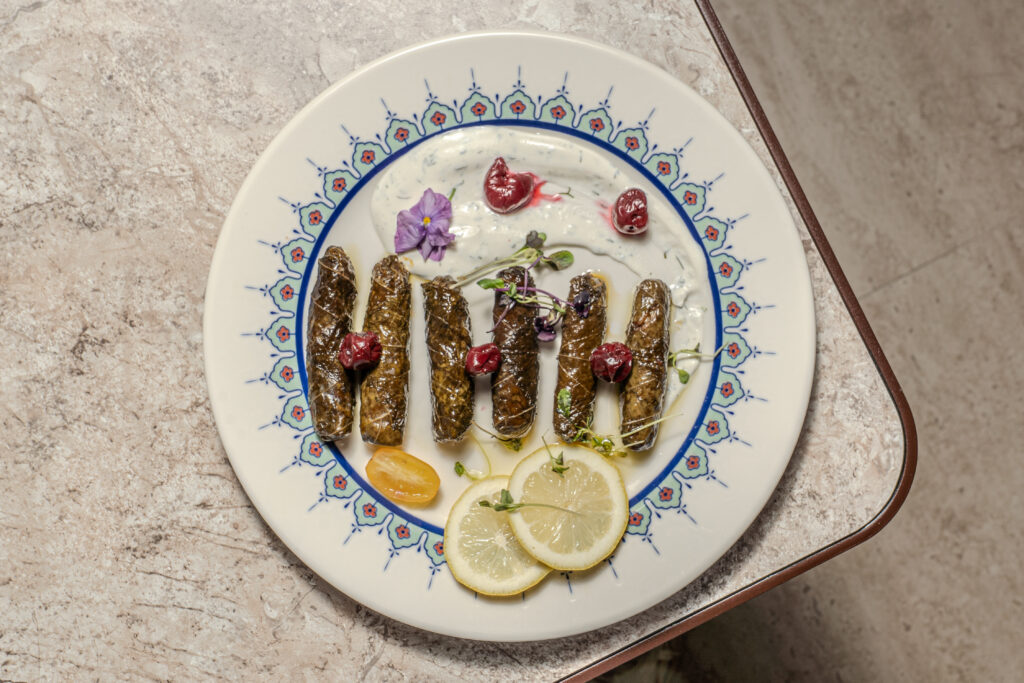 Overhead view of sour cherry grape leaves with lemon slices on a patterned plate at Olivea